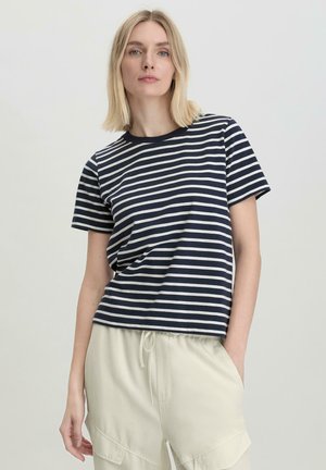 Gestreiftes T-Shirt in Marineblau und Weiß, kurze Ärmel, runder Halsauschnitt, lässige Passform, kombiniert mit hellen Hosen. Mischgewebe aus Baumwolle, weiche Textur.