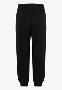 Pantalones de chándal negros, hechos de una tela suave, con una cintura elástica y puños acanalados en los tobillos. Textura lisa, sin patrones visibles.