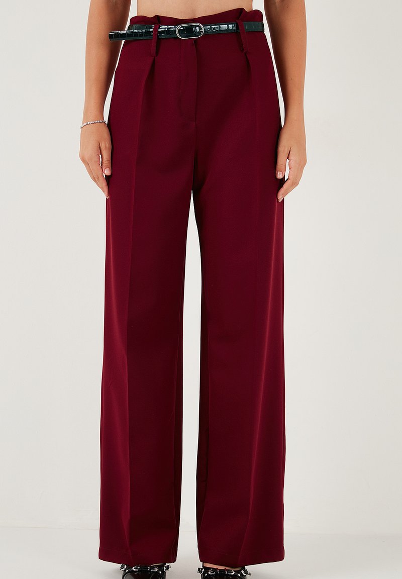 Pantaloni largi burgundy din țesătură netedă, având talie înaltă, pliuri, un curea neagră cu o cataramă lucioasă și o croială ajustată.
