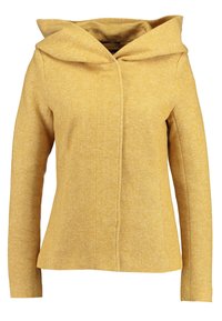 Gul hættejakke med tekstureret stof, der har lukning foran og lange ærmer. Designet er moderne og skræddersyet til et tætsiddende look.