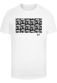 Hvid t-shirt med et gitter af sort-hvide billeder af en karakter med store øjne og en lille mund, mærket "E.T." i hjørnet.