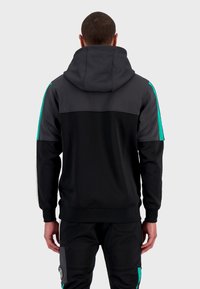 Sudadera con cremallera negra y una capucha grande, con paneles laterales en color verde azulado y puños elásticos, fabricada en un tejido suave y texturizado.