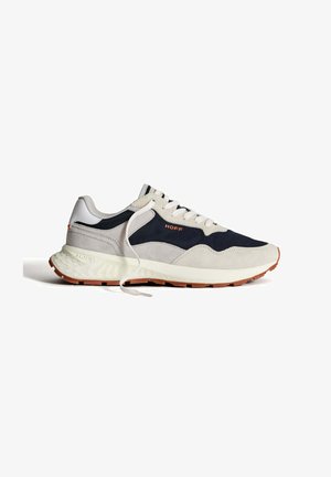 Sneakers gemaakt van grijs suède en marineblauwe stof, met een witte mesh tong, beige zool en oranje "HOFF" branding aan de zijkant.
