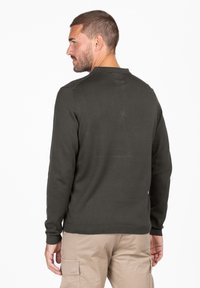 Maglione verde scuro con maniche lunghe, orli a coste e collo rotondo. Il tessuto appare liscio con una sottile texture sul retro.