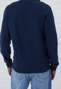 Mörkblå sweatshirt med långa ärmar och rundad hals. Mjuk tygkvalitet med en slät textur. Minimalistisk design, utan synliga mönster eller accenter.