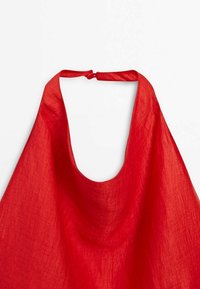 Haut en lin rouge à col halter avec un décolleté plongeant et une petite fermeture à bouton dans le dos.