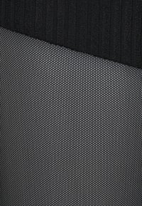 Czarna, prążkowana tkanina nachodzi na delikatny wzór siatki w ciemnoszarym kolorze, ukazując wyraźne tekstury i subtelny połysk.