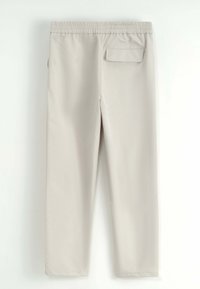 Pantalons droits couleur beige clair avec taille élastique et une seule poche à rabat au dos à droite, vus de l'arrière.