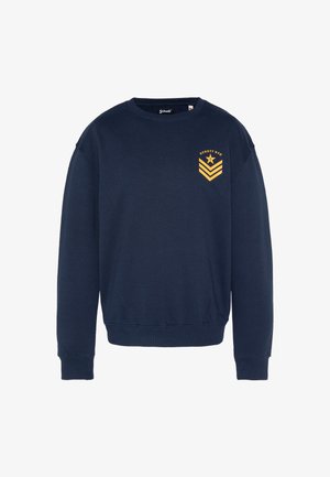Marineblå sweatshirt lavet af bomuld med ribstrikket halsudskæring og manchetter. Har en gul grafisk logo på venstre brystområde.