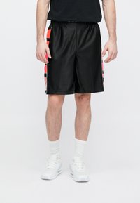 Μαύρο αθλητικό σορτς με υφή, διαθέτει νεον πορτοκαλί πλαϊνές λωρίδες και μαύρες λεπτομέρειες. Ελαστική μέση και άνετη εφαρμογή.