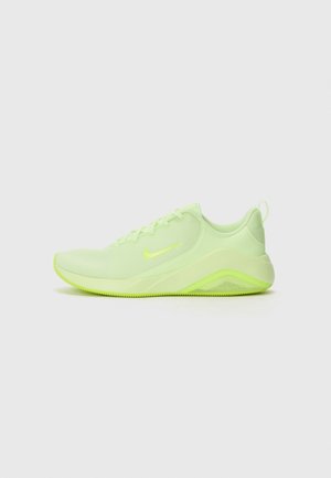 Zapatilla de correr Nike verde claro con parte superior de malla, cierre de cordones, suela acolchada y lengüeta en el talón sobre un fondo claro y liso.