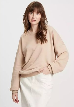 Beżowy, oversize'owy sweter z długimi rękawami i ściągaczami. Wykonany z miękkiego materiału, z okrągłym dekoltem i luźnym fasonem. Białe wykończenie na dole.