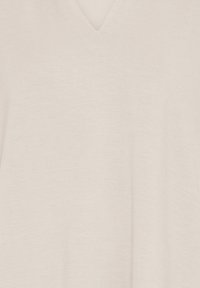 Haut en maille sans manches beige clair avec col en V et texture lisse, présenté sur un fond neutre.