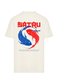 Cream t-shirt featuring blue and red koi fish graphics with stylized text. Soft cotton material, relaxed fit, and short sleeves.