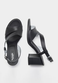 Sandali in pelle nera con fasce incrociate, fibbia regolabile alla caviglia e tacco spesso a righe. Texture liscia e design minimalista.
