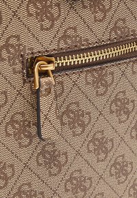 Bolso de tela marrón con estampado y una cremallera dorada, que presenta un material texturizado y una pequeña pestaña. Elementos de diseño geométrico notables.