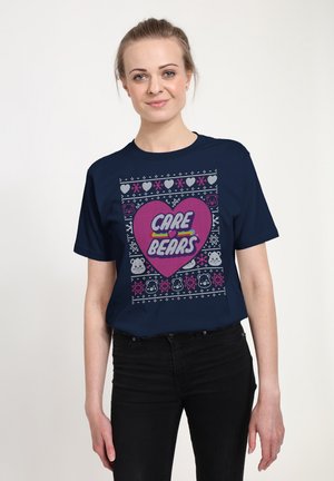 Marineblå t-shirt med frontgrafik, der har et pink hjerte og teksten "CARE BEARS", dekoreret med farverige mønstre og bjørneikoner.