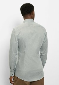 Hellblaues Hemd mit Knopfleiste, geometrischem Muster, langen Ärmeln und einem Kentkragen. Es verfügt über geknöpfte Manschetten und einen abgerundeten Saum.