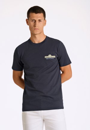 Camiseta de algodón azul marino con mangas cortas y escote redondo; presenta un gráfico frontal que dice "DOBLE LAS REGLAS" con un diseño circular.