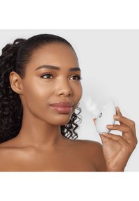 Dispositif de brumisation portatif, blanc, en forme ovale avec une texture lisse, doté d'un bouton central et émettant une fine brume.
