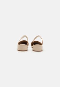 Beige Sandalen mit offenem Rücken aus glattem Material, breiten Riemen und einem niedrigen, stabilen Absatz. Einfaches Design ohne Muster oder Verzierungen.