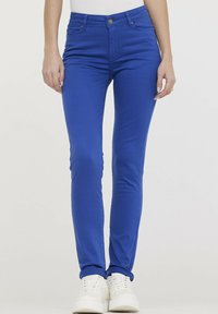 Jean skinny bleu en tissu extensible, avec une texture lisse, un design à cinq poches et une fermeture à bouton en métal à la taille.