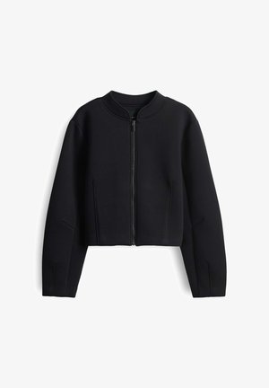 Black cropped jacket made from smooth fabric. Features a high collar and a front zipper. Includes subtle seam detailing on sleeves.