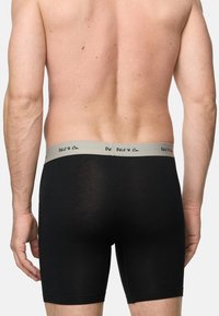 Svarta boxerkalsonger med en grå midjeband som har "Phil & Co"-logotypen. Stretchigt material med en slät yta, knälång klipp.