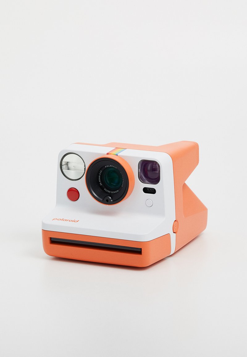 Polaroid camera with a white body and orange accents, circular lens, flash, and a colored stripe; square film output at the bottom.