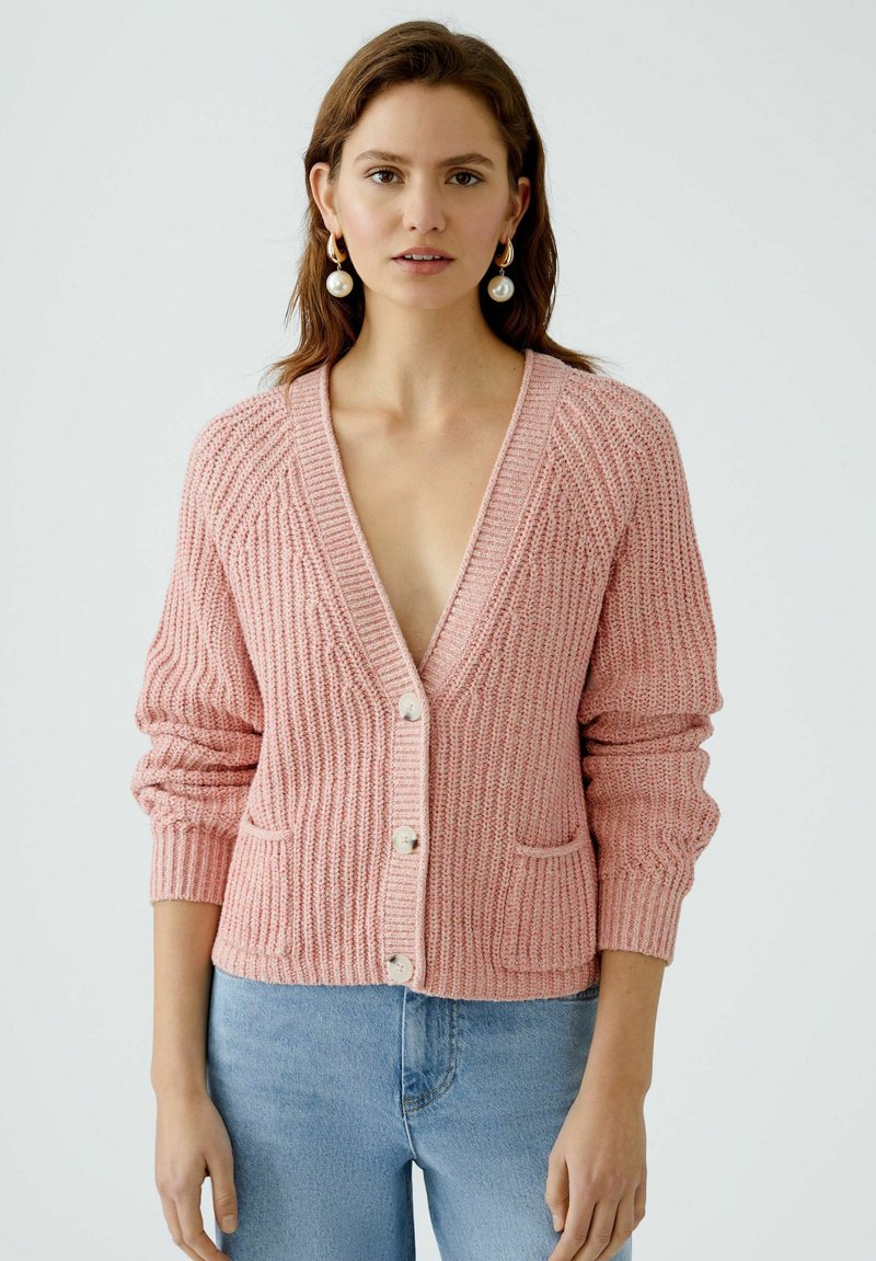 Rosa gestrickte Strickjacke mit tiefem V-Ausschnitt, langen Ärmeln, vorderen Taschen und Knopfverschluss. Strukturiertes, geripptes Material. Lässige Passform.
