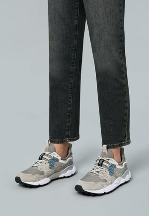 Gray suede and mesh sneakers with black rubber soles, featuring blue accents and a padded collar, paired with dark denim.