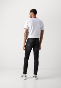 Tricou alb din bumbac, cu mâneci scurte, croială lejeră. Jeanși negri din denim, cu o croială slim și buzunare pe spate. Tenisi albi cu accente negre.