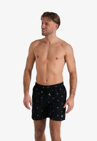 Zwarte zwembroek met een trekkoord in de taille, met een groen palmboomontwerp. Gemaakt van een lichtgewicht, sneldrogend materiaal.