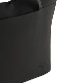 Sac en textile noir avec une texture lisse, une forme structurée et un logo brodé subtil près de la base. Design minimaliste.