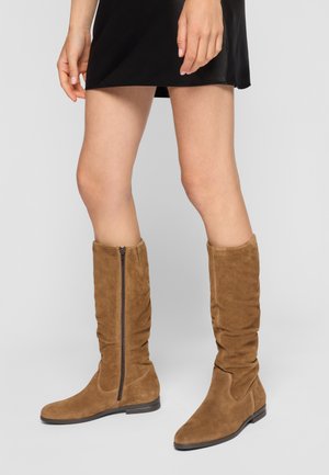 Bottes en daim marron hauteur genou avec une fermeture éclair sur le côté et un design flou, présentant un bout rond et un petit talon carré.