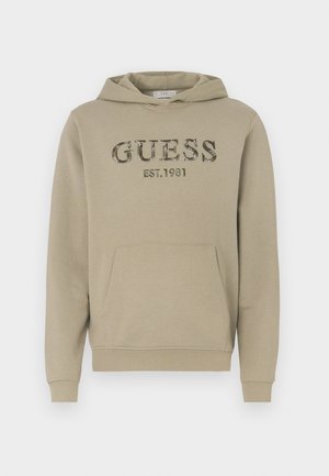 Hanorac bej din amestec de bumbac, cu buzunar frontal tip kangaroo, manșete ribbate și logo-ul "GUESS EST.1981" cu textură de camuflaj.