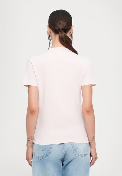 Helles rosa Kurzarm-T-Shirt aus weicher Baumwolle mit Rundhalsausschnitt. Getragen mit hellblauen, verwaschenen Jeans.