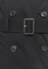 Schwarzer Trenchcoat mit tailliertem Gürtel, doppelreihigem Design, großen Knöpfen und glatter Stoffstruktur.