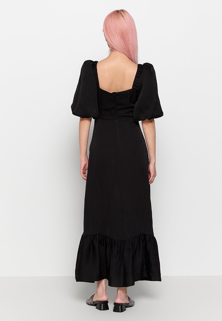 Schwarzes Kleid mit Puffärmeln, quadratischem Rücken und gerüschtem Saum. Aus strukturiertem Stoff gefertigt, verfügt es über ein tailliertes Oberteil und einen fließenden Rock.