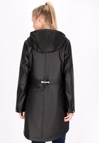 Lungo cappotto nero impermeabile con cappuccio, vita regolabile con cordoncino e texture liscia; presenta accessori in argento sulla vita e sui polsini.