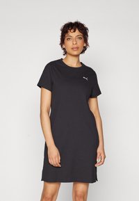 Vestido de camiseta negro de canalé con mangas cortas y escote redondo. Presenta un pequeño logo blanco en el pecho y aberturas laterales en el dobladillo.