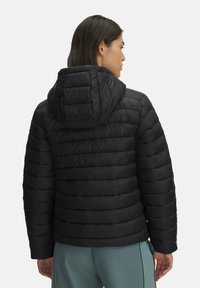 Must must vest, mille horisontaalne tikand, kinnitatud kapuuts ja elastsed mansetid. Sile, kerge ja veekindel materjal.