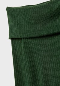 Tissu en maille côtelée verte avec revers plié, montrant une texture verticale et un détail de matériau doux.