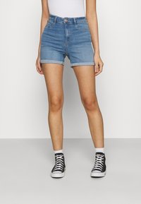 Shorts in denim a vita alta color azzurro chiaro, con orli risvoltati e tasche frontali. Abbinati a sneakers alte nere e calzini bianchi alla caviglia.