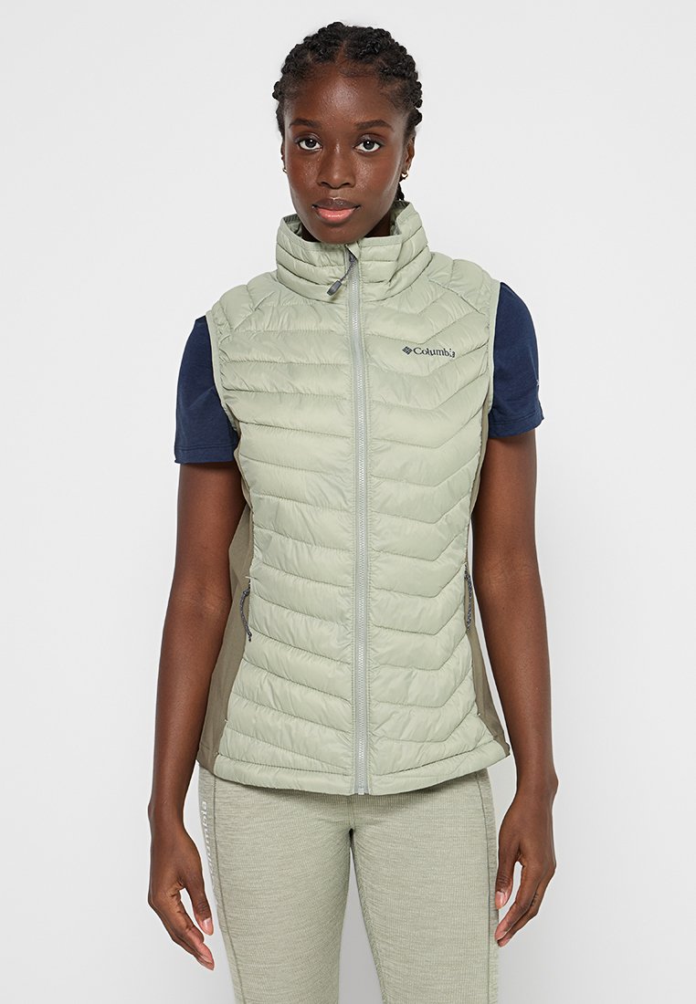 Gilet imbottito verde chiaro con colletto alto, chiusura con zip e tasche laterali. Presenta una texture liscia e il logo Columbia sul petto.