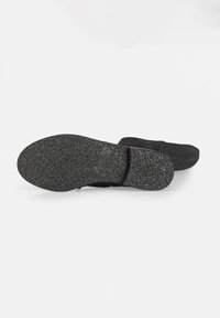 Black shoe sole featuring a textured rubber material, flat design with a slightly curved toe, and embossed brand detailing.