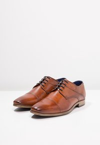 Chaussures de ville en cuir marron à bout pointu, avec un dos texturé, un design à lacets et une semelle en bois.