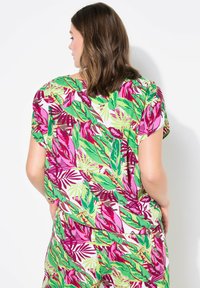 Camicia a maniche corte con un vivace motivo floreale, con foglie rosa e verdi su uno sfondo bianco. Tessuto leggero e traspirante.