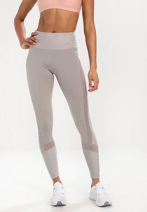 Leggings gris clair avec une taille haute et des accents en maille sur les côtés. Fabriqués en tissu extensible pour le confort et la flexibilité.