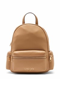 Mochila de cuero color coñac con forma redondeada, que cuenta con un bolsillo frontal con cremallera y detalles en herrajes dorados. Logotipo en relieve en la parte inferior.